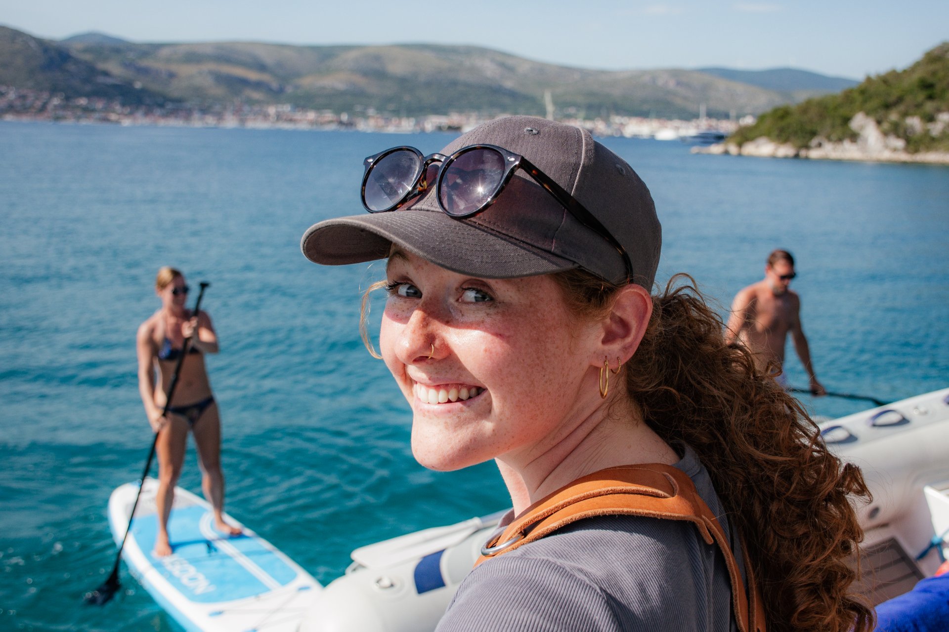 Gäste beim Stand-up-Paddling in einer türkisblauen Bucht während eines Segelurlaubs in Kroatien