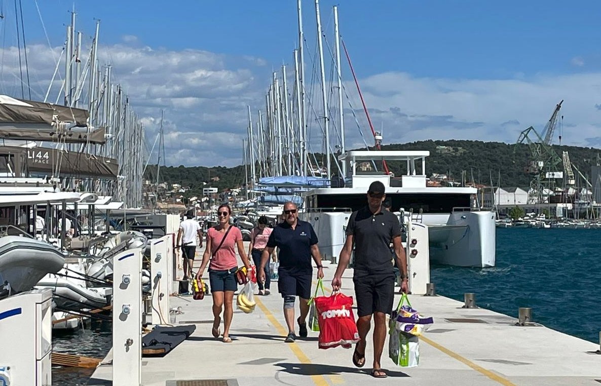 Eine Segel-Crew trägt Einkäufe zum Schiff.