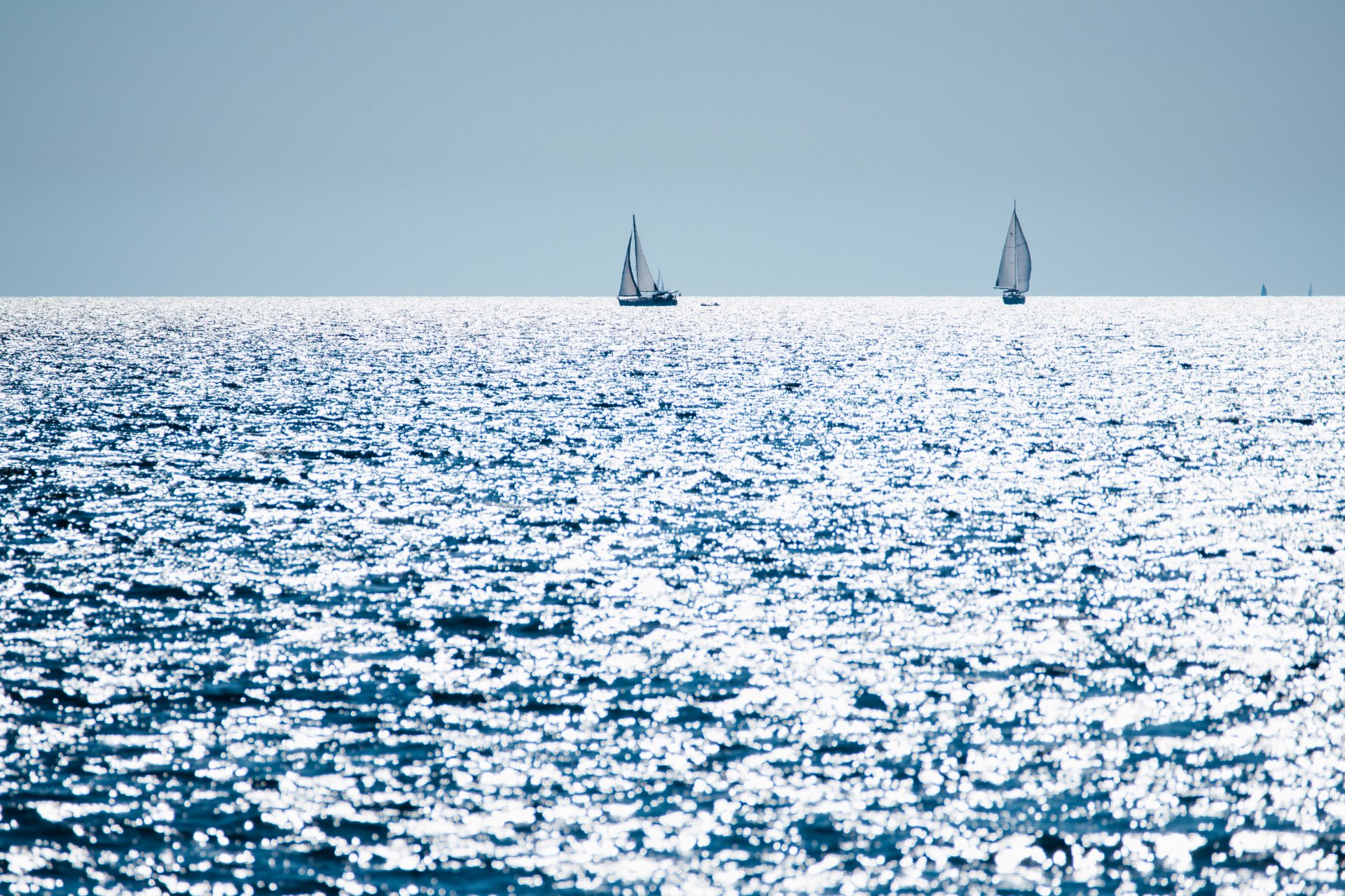 Das Meer der kroatischen Adria im gleissenden Sonnenlicht mit Segelyachten am Horizont.
