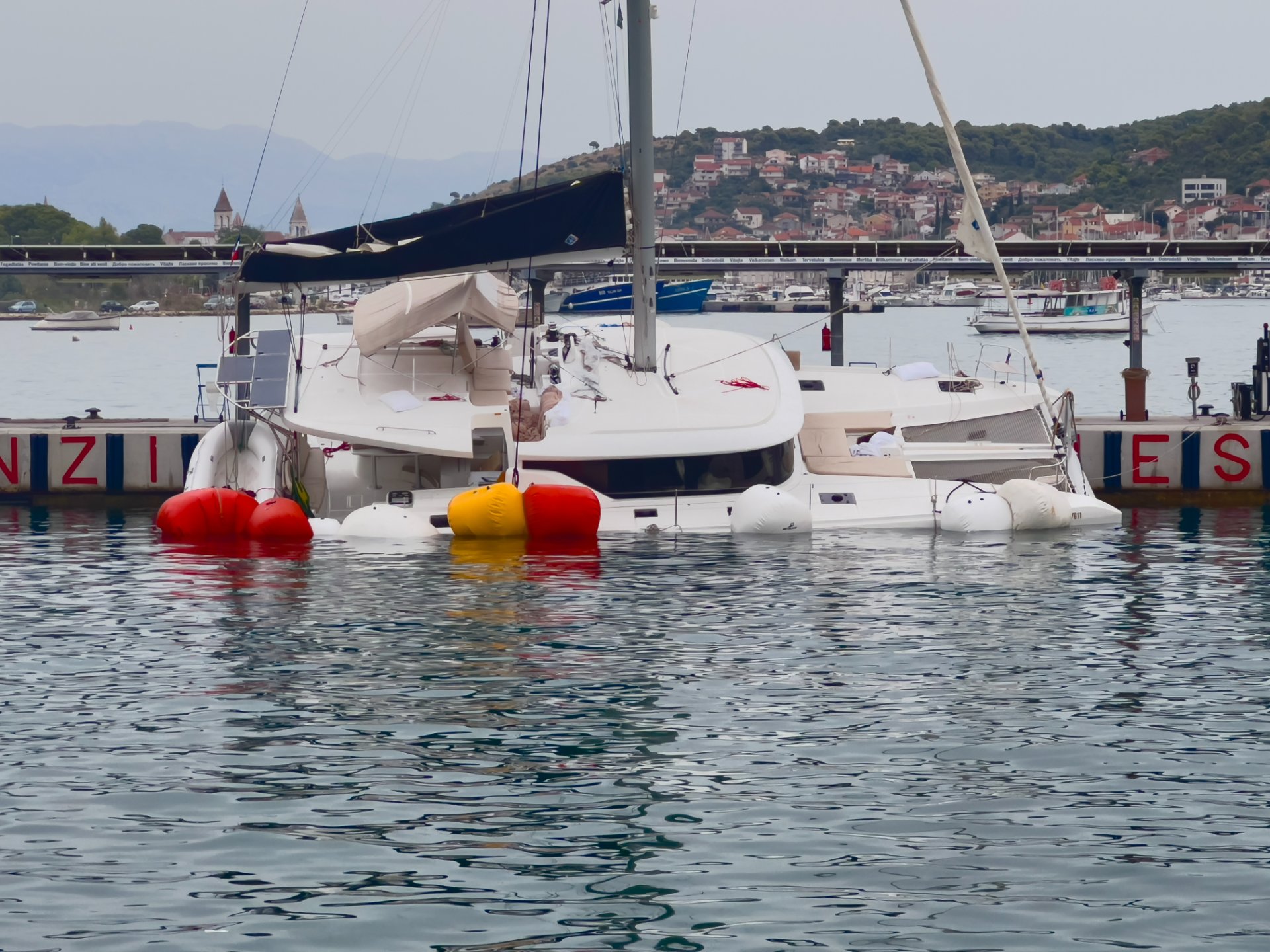 Ein leckgeschlagener Katamaran mit Schwimmkörpern in der Marina. Ein leckgeschlagener Katamaran mit Schwimmkörpern in der Marina.